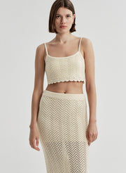 Woman wearing a beige knit cropped top and matching skirt on a light gray background