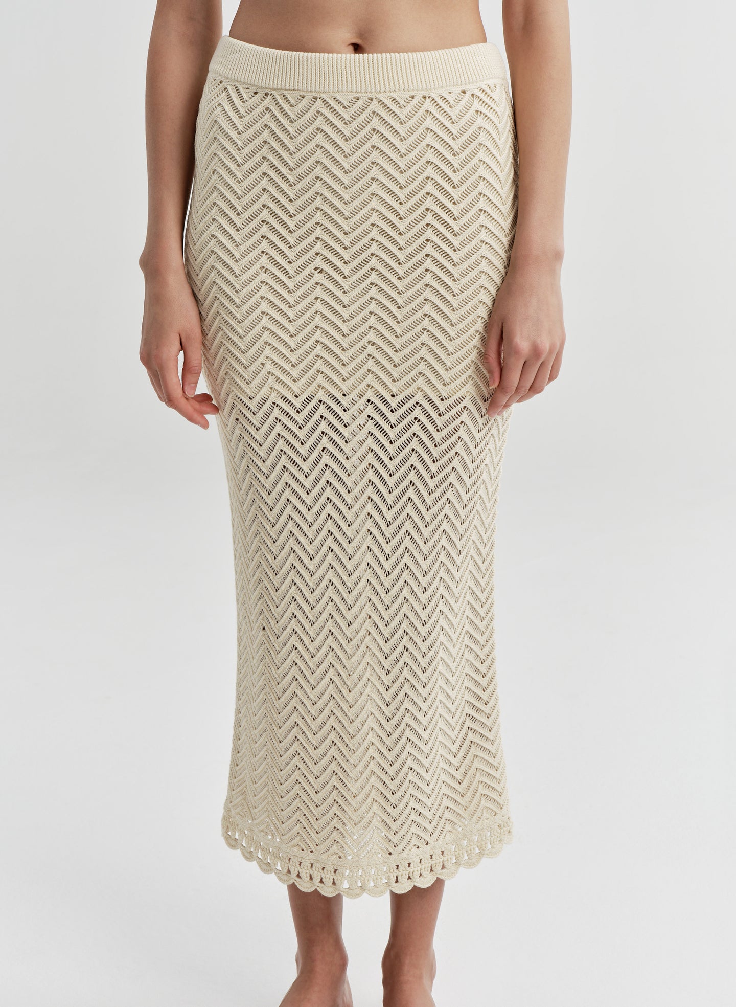 Beige knitted skirt worn by a woman on a white background