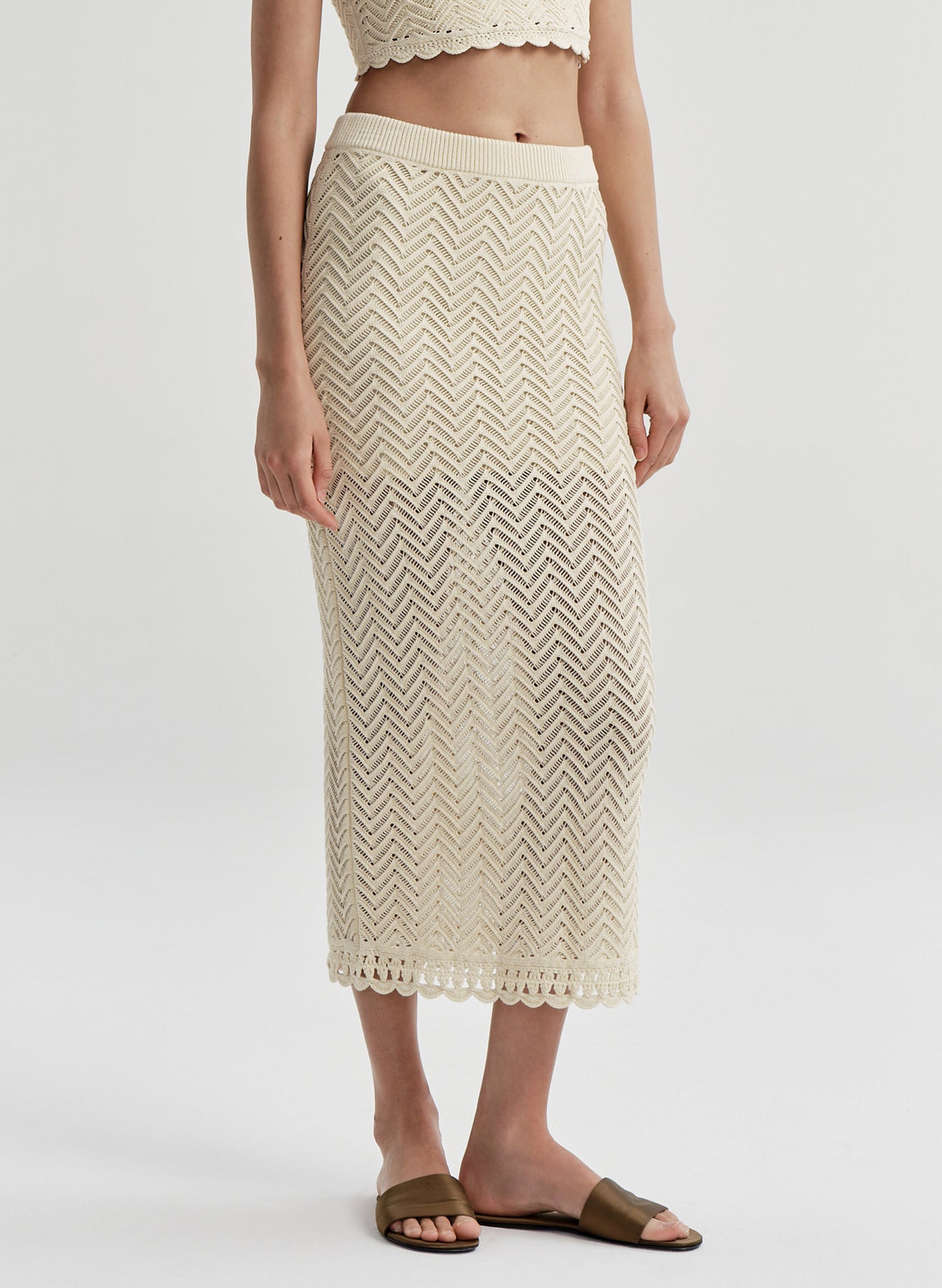 Woman wearing a beige crochet skirt on a white background