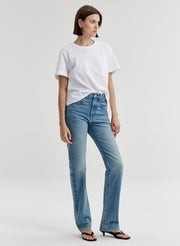 Woman wearing a white t-shirt and blue jeans on a light gray background