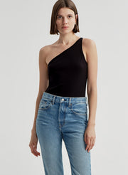 Woman wearing a black one-shoulder top and blue jeans on a light gray background