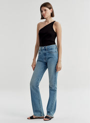 Woman wearing a black one-shoulder top and blue jeans on a light gray background