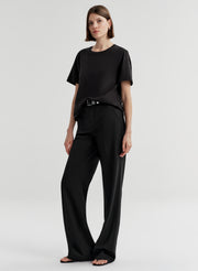 Woman wearing a black t-shirt and black pants on a light gray background