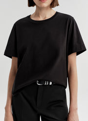 Woman wearing a black t-shirt and black pants on a light gray background