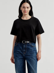 Woman wearing a black t-shirt and blue jeans on a light gray background