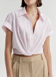Person wearing a light pink short-sleeve shirt with a plain background