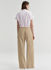 Person wearing a pink shirt and beige pants on a light gray background