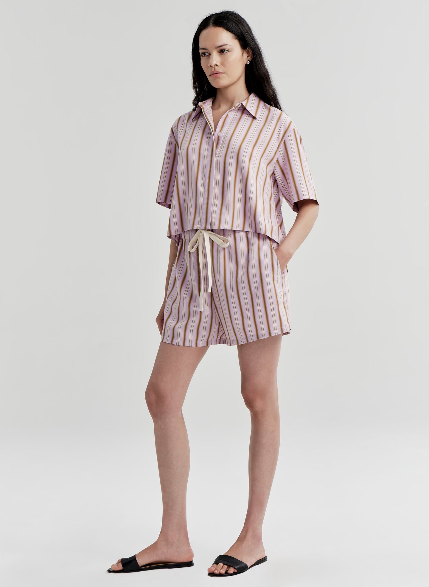 Woman wearing a striped shirt and shorts set on a plain background