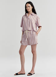 Woman wearing a striped shirt and shorts set on a plain background