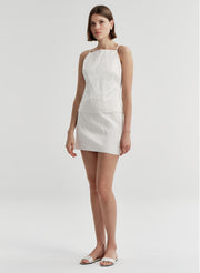 Woman wearing a cream sleeveless top against a plain background