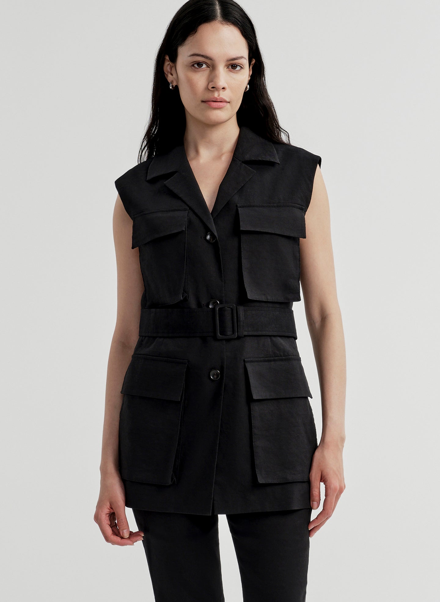 Woman wearing a black sleeveless vest with multiple pockets on a light gray background