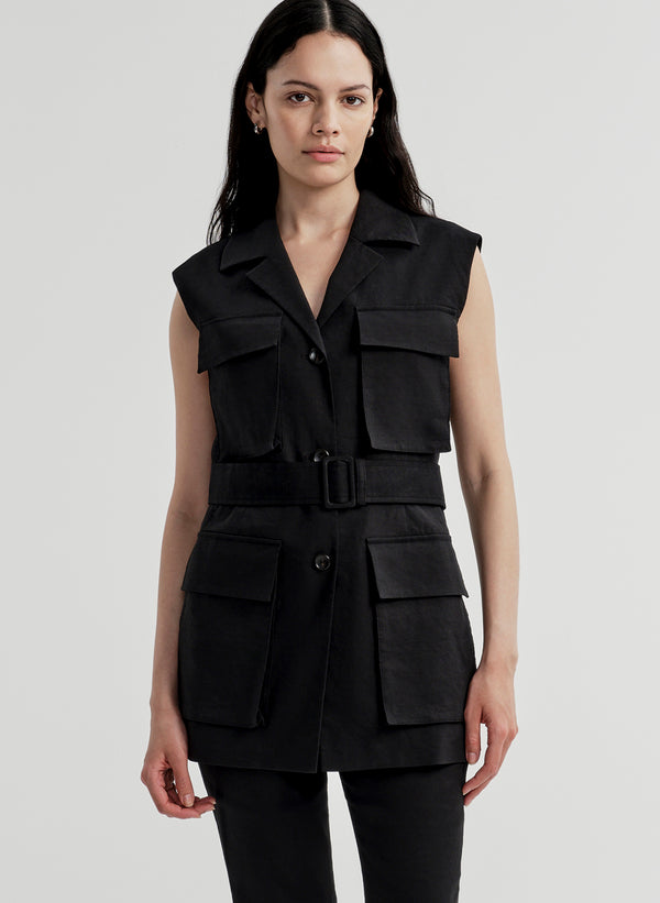 Woman wearing a black sleeveless vest with multiple pockets on a light gray background