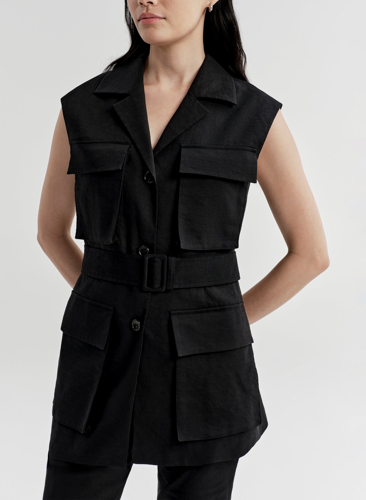 Woman wearing a black sleeveless vest with multiple pockets on a light gray background