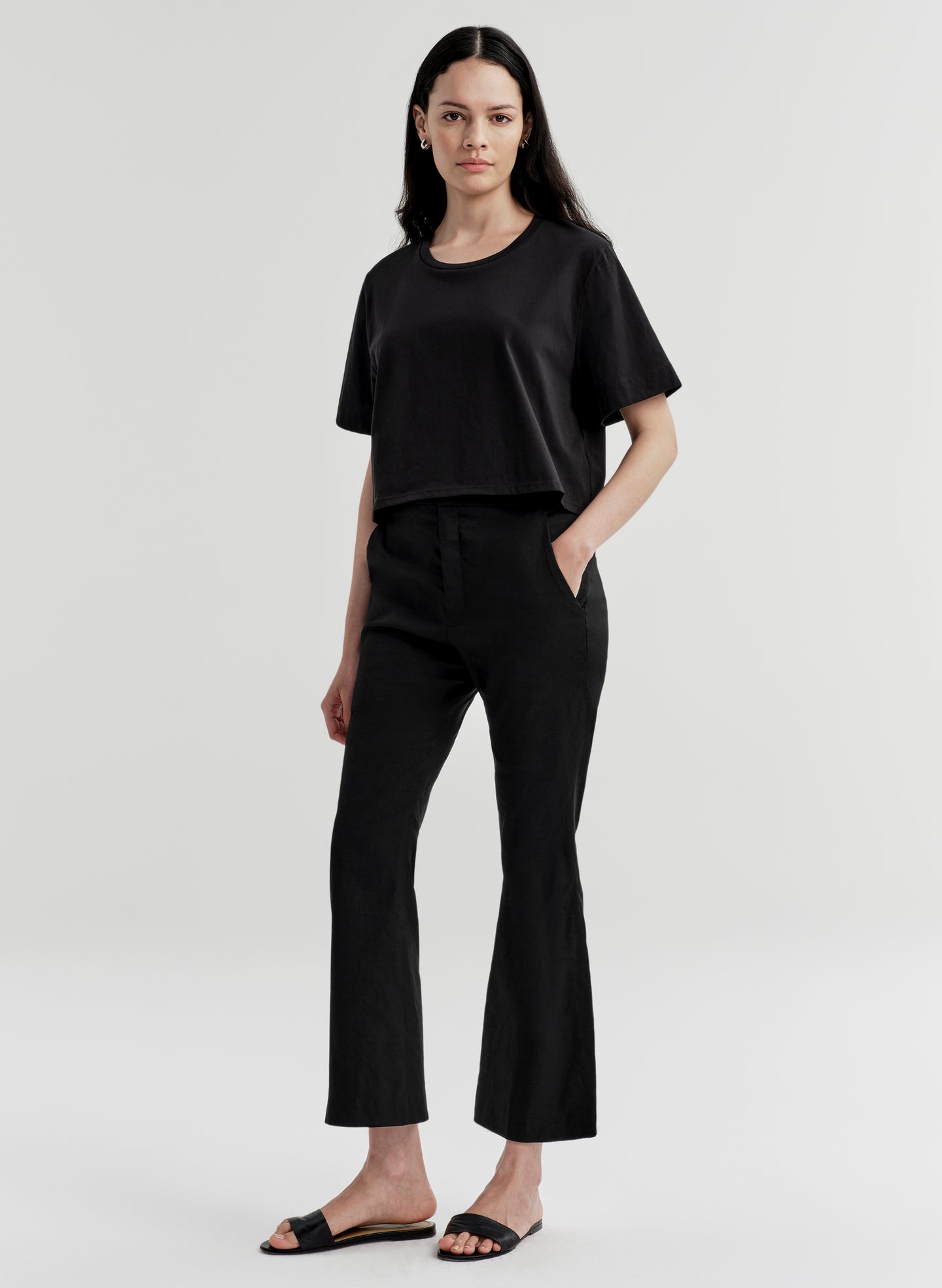 Woman wearing black linen pants with a black top on a white background