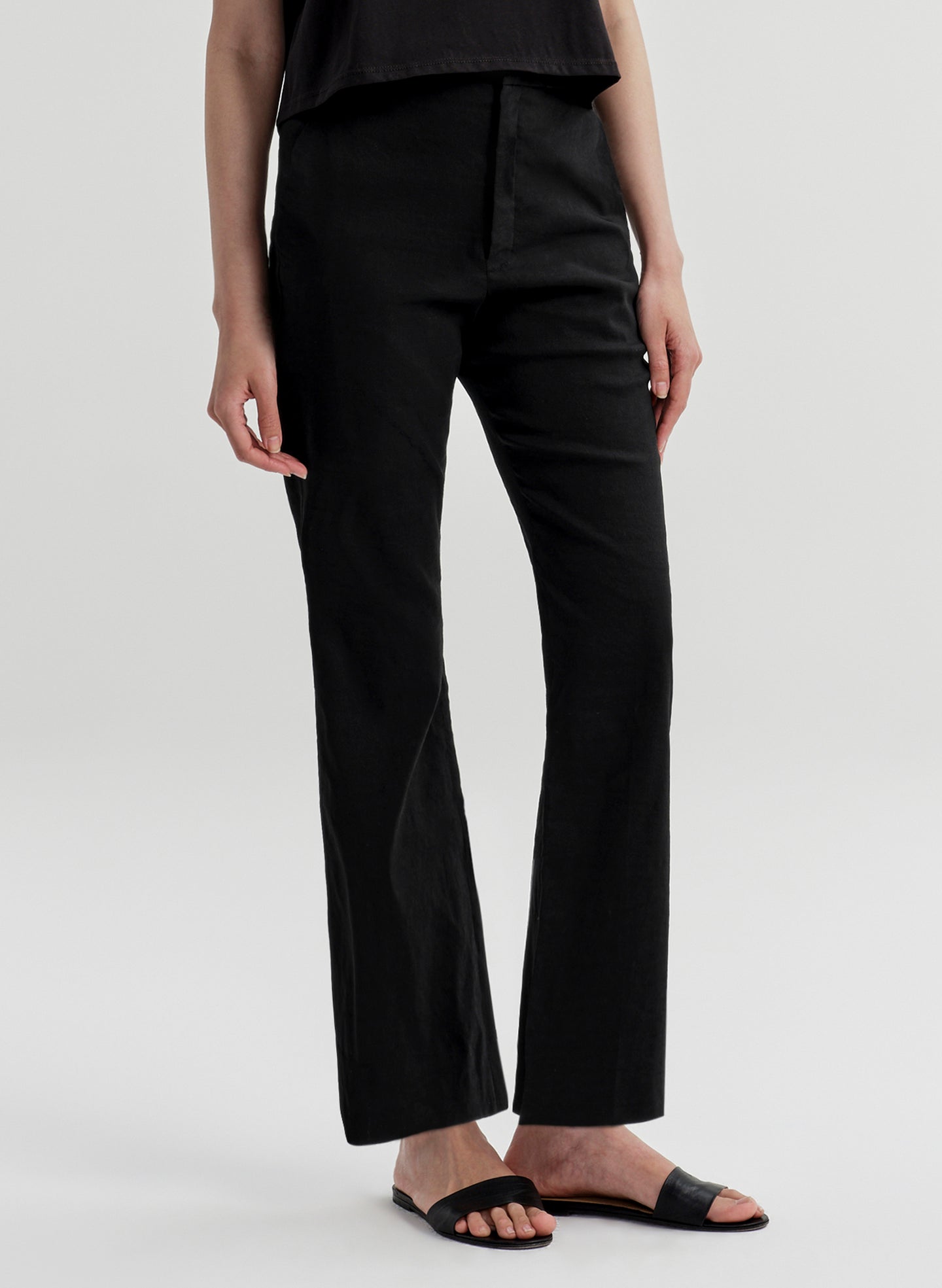 Woman wearing black linen pants with a black top on a white background