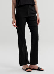 Woman wearing black linen pants with a black top on a white background