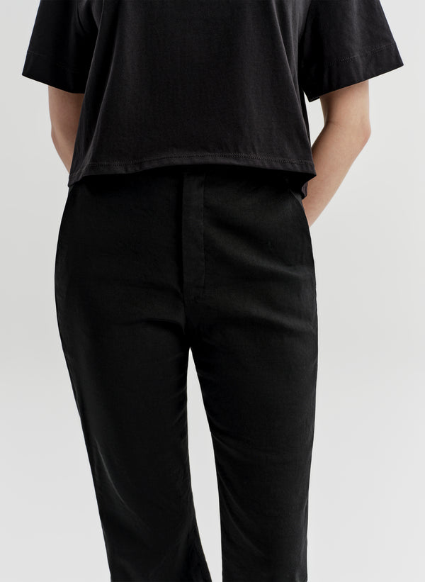 Woman wearing black linen pants with a black top on a white background