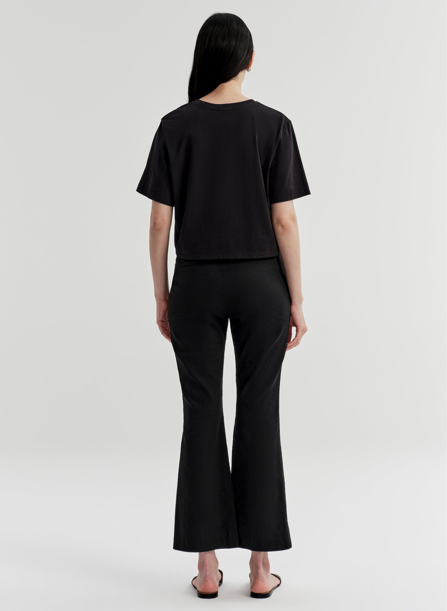 Woman wearing black linen pants with a black top on a white background