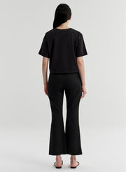 Woman wearing black linen pants with a black top on a white background