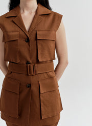 Woman wearing a brown sleeveless vest jacket with a belt and pockets on a white background