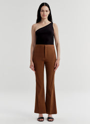 Woman wearing brown linen pants and a black top on a white background