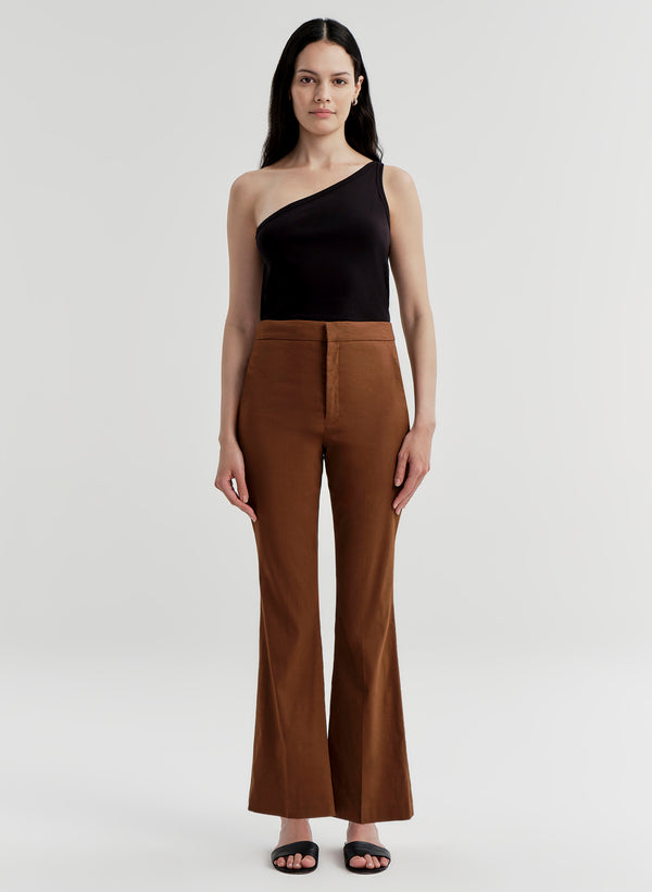 Woman wearing brown linen pants and a black top on a white background