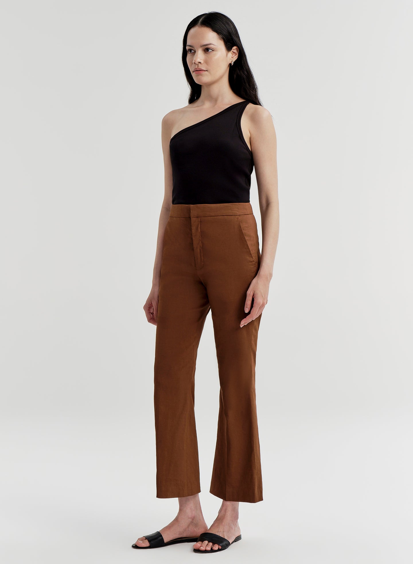 Woman wearing a black top and brown pants on a white background