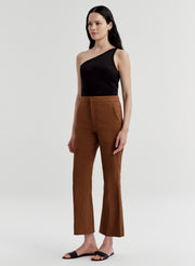 Woman wearing a black top and brown pants on a white background