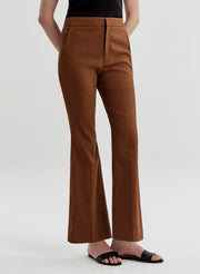 Woman wearing brown linen pants and a black top on a white background
