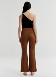 Woman wearing brown linen pants and a black top on a white background