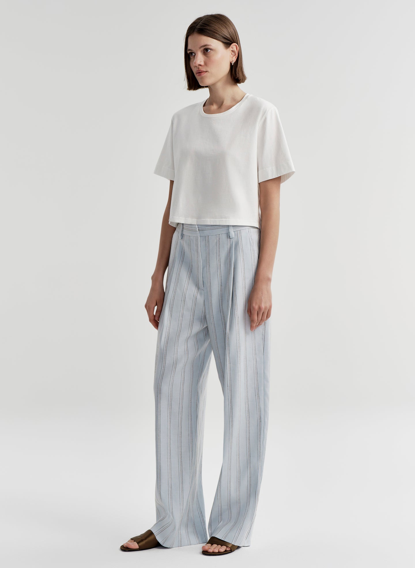 Woman wearing striped linen pants with a white top on a white background