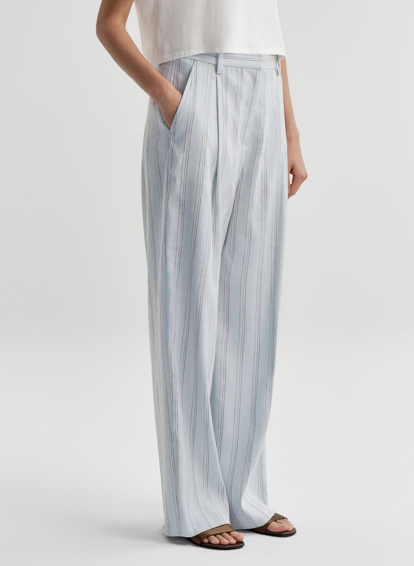 Woman wearing striped linen pants with a white top on a white background