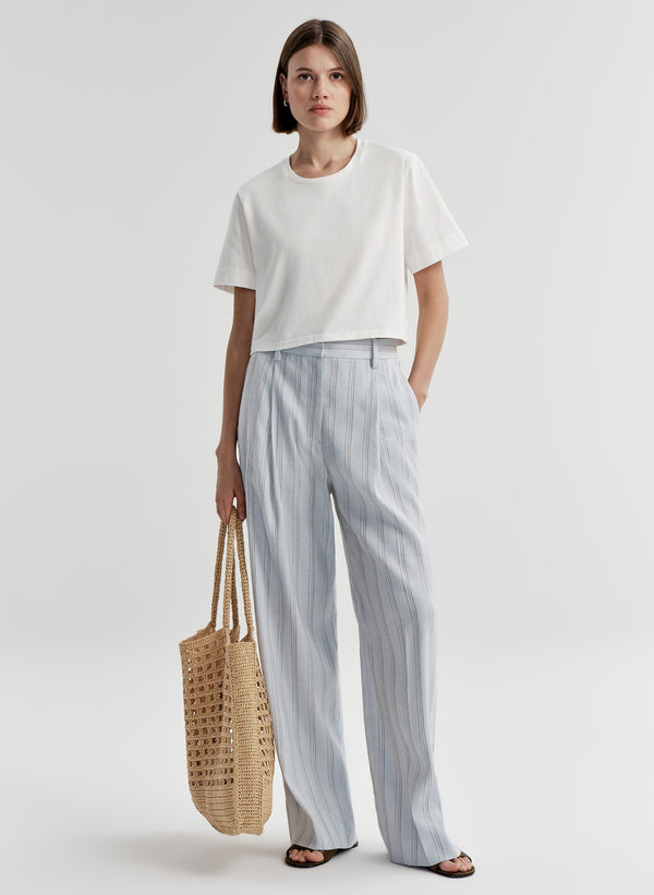 Woman wearing striped linen pants with a white top on a white background