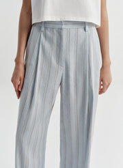 Woman wearing striped linen pants with a white top on a white background