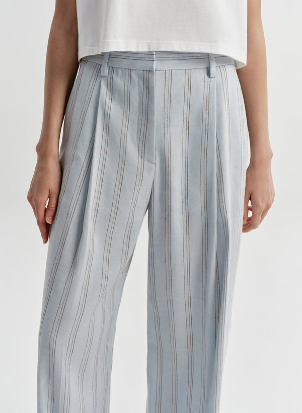 Woman wearing striped linen pants with a white top on a white background