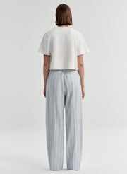Woman wearing striped linen pants with a white top on a white background