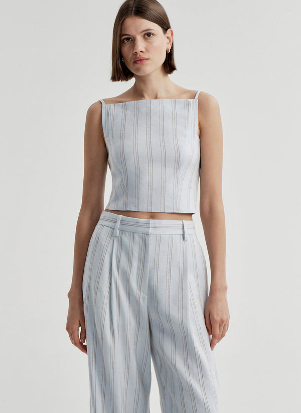Woman wearing a light blue striped sleeveless top and matching pants on a white background