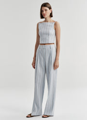Woman wearing a light blue striped sleeveless top and matching pants on a white background