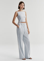 Woman wearing a light blue striped sleeveless top and matching pants on a white background