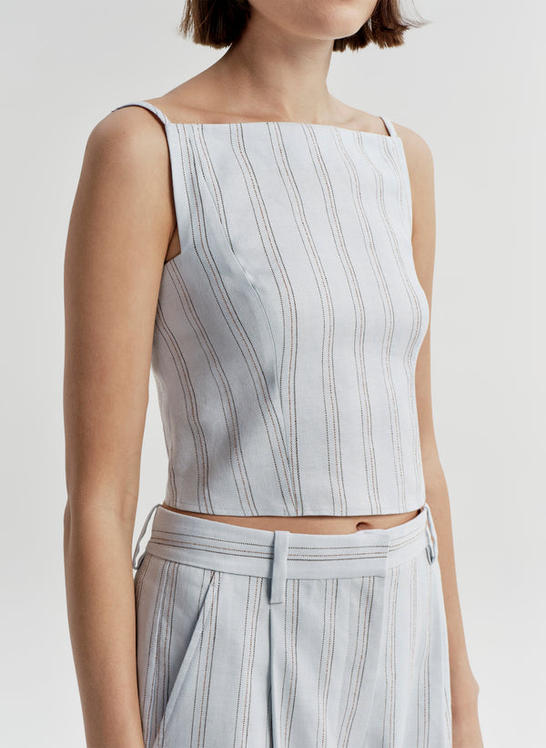 Woman wearing a light blue striped sleeveless top and matching pants on a white background