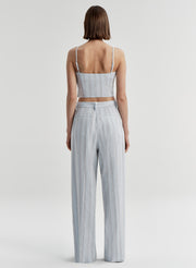 Woman wearing a light blue striped sleeveless top and matching pants on a white background