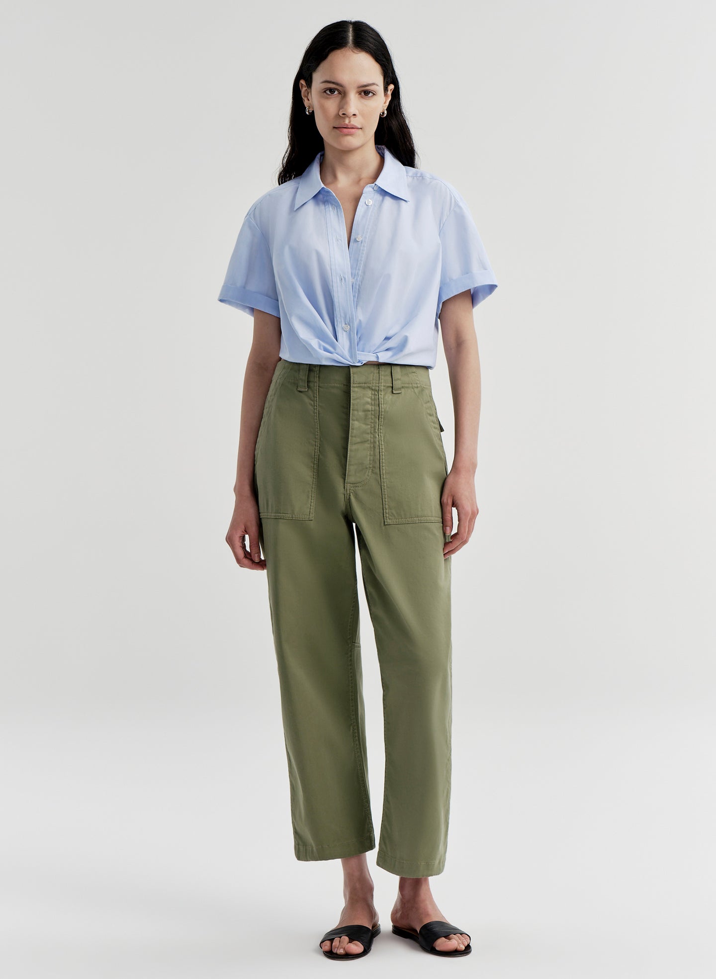 Woman wearing green pants with a light blue shirt on a white background