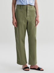 Woman wearing green pants with a light blue shirt on a white background