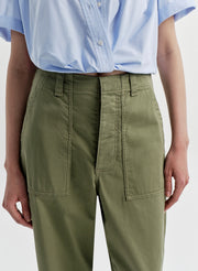 Woman wearing green pants with a light blue shirt on a white background
