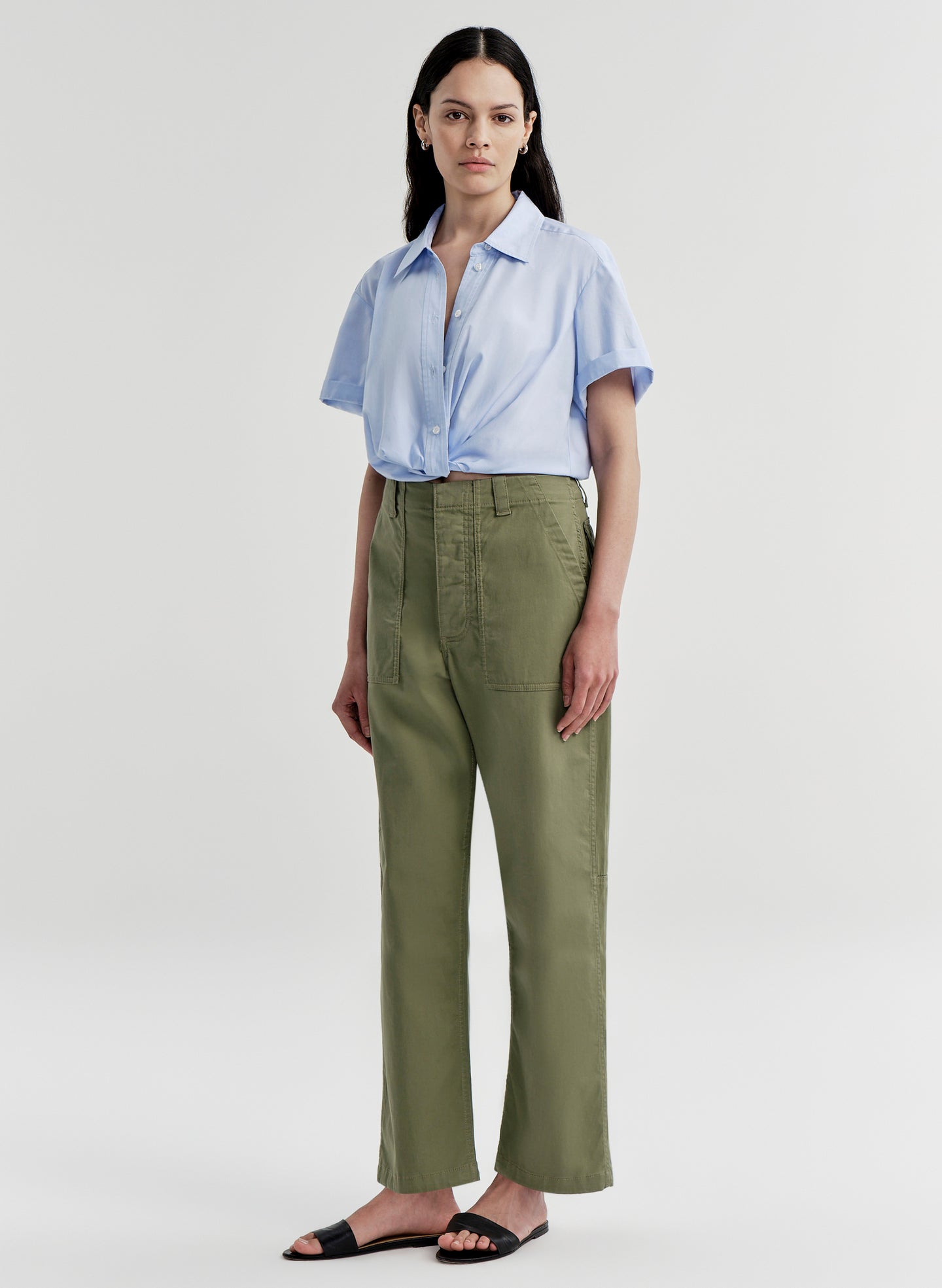 Woman wearing green pants with a light blue shirt on a white background
