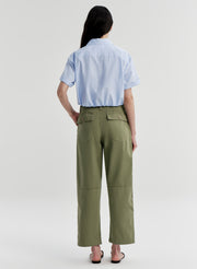 Woman wearing green pants with a light blue shirt on a white background