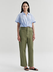 Woman wearing a light blue shirt and green pants on a white background