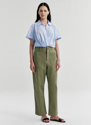 Woman wearing a light blue shirt and green pants on a white background