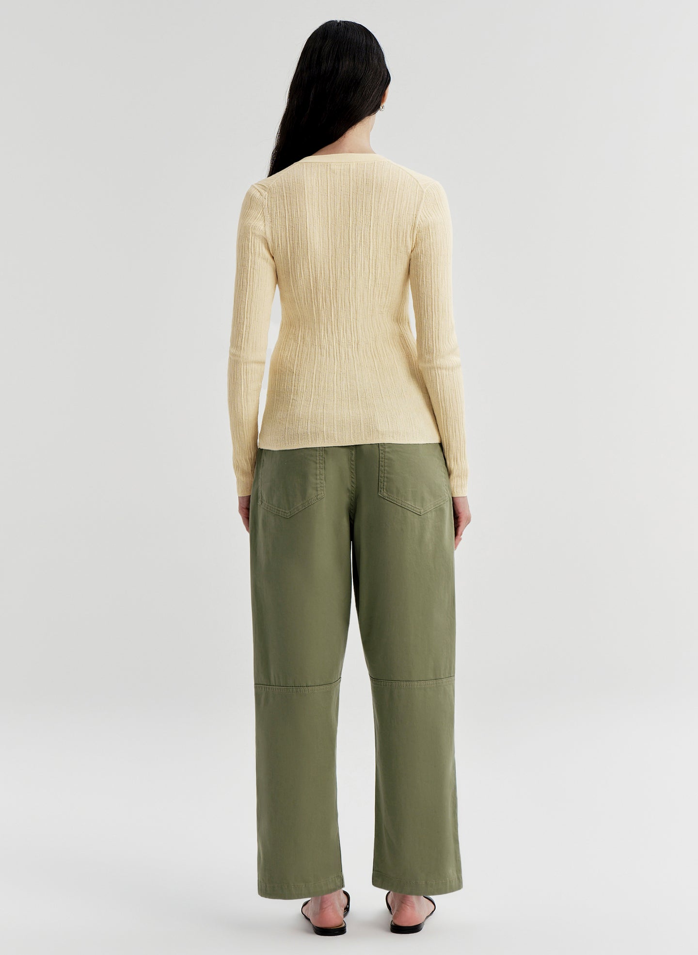 Woman wearing a yellow sweater and green pants on a white background
