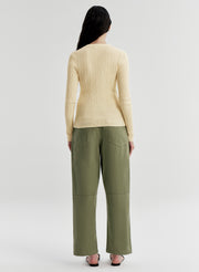 Woman wearing a yellow sweater and green pants on a white background